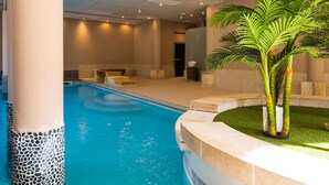 A swimming pool with a stone border, a bench, and a palm tree. - Central apartment with balcony, pool and secure parking (Saint-Lary-Soulan)