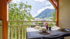 Ein Balkon mit Tisch für zwei Personen, mit Blick auf eine gebirgige Landschaft.