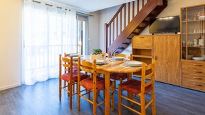 A dining area with a wooden table and chairs, a staircase, and a TV cabinet.