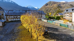 A hotel with a parking lot, a tree-lined driveway, and a mountain backdrop.