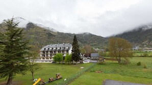 Un hotel con un edificio grande, un área de juegos y montañas al fondo.