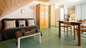 A cozy room with a wooden ceiling, a sofa with patterned cushions, a small bench with plants, and a dining area with a table and chairs. - Quiet apartment, 8 people, near center, parking, Saint Lary Soulan (Saint-Lary-Soulan)