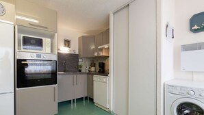 A compact kitchen with a built-in oven, microwave, and dishwasher, and a washing machine in the adjacent room. - Quiet apartment, 8 people, near center, parking, Saint Lary Soulan (Saint-Lary-Soulan)