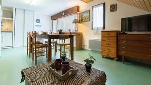 A cozy living room with a wooden dining table, chairs, a TV, and a sofa. - Quiet apartment, 8 people, near center, parking, Saint Lary Soulan (Saint-Lary-Soulan)