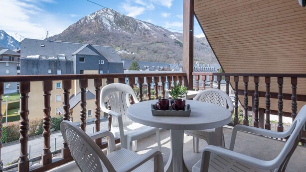 A balcony with a wooden railing, white plastic chairs, and a round table with two red mugs and a potted plant. - Quiet apartment, 8 people, near center, parking, Saint Lary Soulan (Saint-Lary-Soulan)