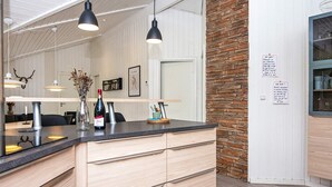 A modern kitchen with a central island, pendant lighting, and a stone accent wall. - Luxury Spa Retreat in Arrild - By Traum Ferienwohnungen (Toftlund)