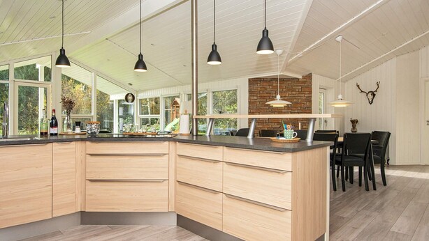 A modern kitchen with a large island, pendant lighting, and a dining area with chairs. - Luxury Spa Retreat in Arrild - By Traum Ferienwohnungen (Toftlund)