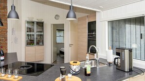 A modern kitchen with a central island, black countertops, and pendant lighting. - Luxury Spa Retreat in Arrild - By Traum Ferienwohnungen (Toftlund)