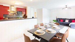 A modern kitchen with red cabinets, a central island, and a dining area with a table set for four.