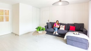 A modern living room with a grey sofa, a small round coffee table, and a potted plant.