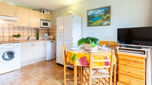 A compact kitchen with a microwave, washing machine, and a dining area with a table set for two. - Quiet Apartment near Saint-Lary Center, 700m from Cable Car, Max 5 People (Saint-Lary-Soulan)