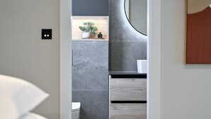 A modern bathroom with a grey and white color scheme, a round mirror, and a small plant on the countertop. - Villa Azzurra Zadarvillas (Sukosan)