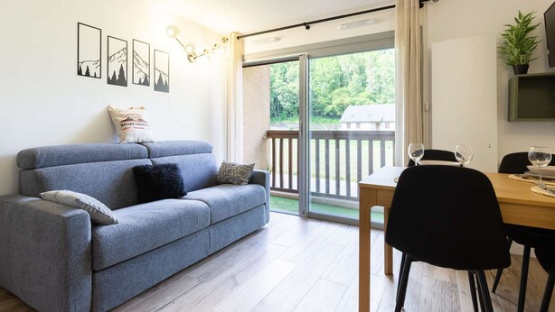A modern living room with a grey sofa, a dining table with chairs, and a sliding glass door leading to a balcony. - Quiet apartment Saint Lary, 4 people, near center, wifi included (Saint-Lary-Soulan)