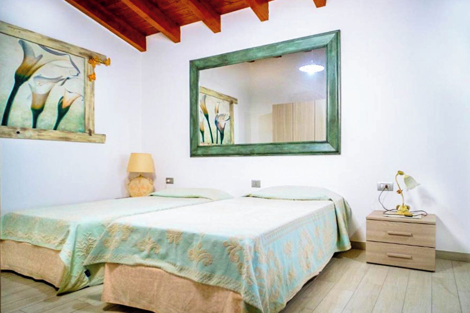 Una camera da letto con due letti, un comodino, una lampada e uno specchio.