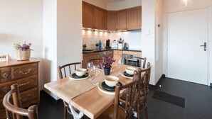 A modern kitchen with wooden cabinets, a dining table set for four, and a small plant on the sideboard.