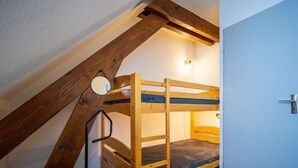 Ein Stockbett in einem Zimmer mit schrägen Decken und freiliegenden Holzbalken.