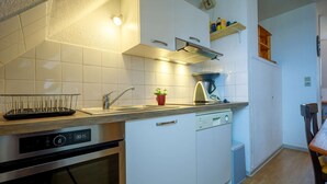 Eine moderne Küche mit weißen Schränken, einem Edelstahlbackofen, einer Spülmaschine und einer Kaffeemaschine.