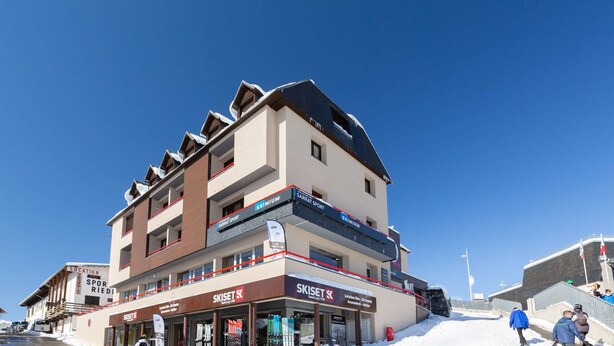 Ein mehrstöckiges Gebäude mit Hinweisschildern zum Thema Skifahren, darunter 'SKISET' und 'SKIMIUM'.