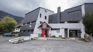 Un bâtiment avec une entrée rouge, une enseigne indiquant « Royal Milan » et un espace de stationnement devant.