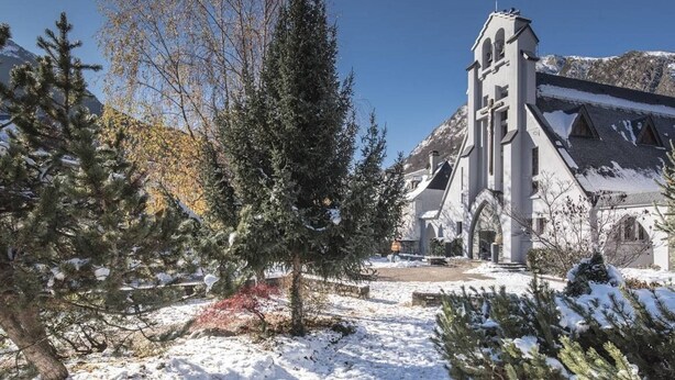 Un paysage enneigé avec une église et une montagne en arrière-plan.