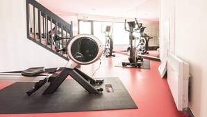 Une salle de sport équipée de matériel d’exercice, avec un tapis noir et un escalier.