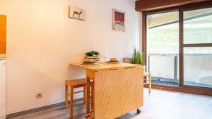 A small kitchen area with a wooden table, a bench, and a potted plant.