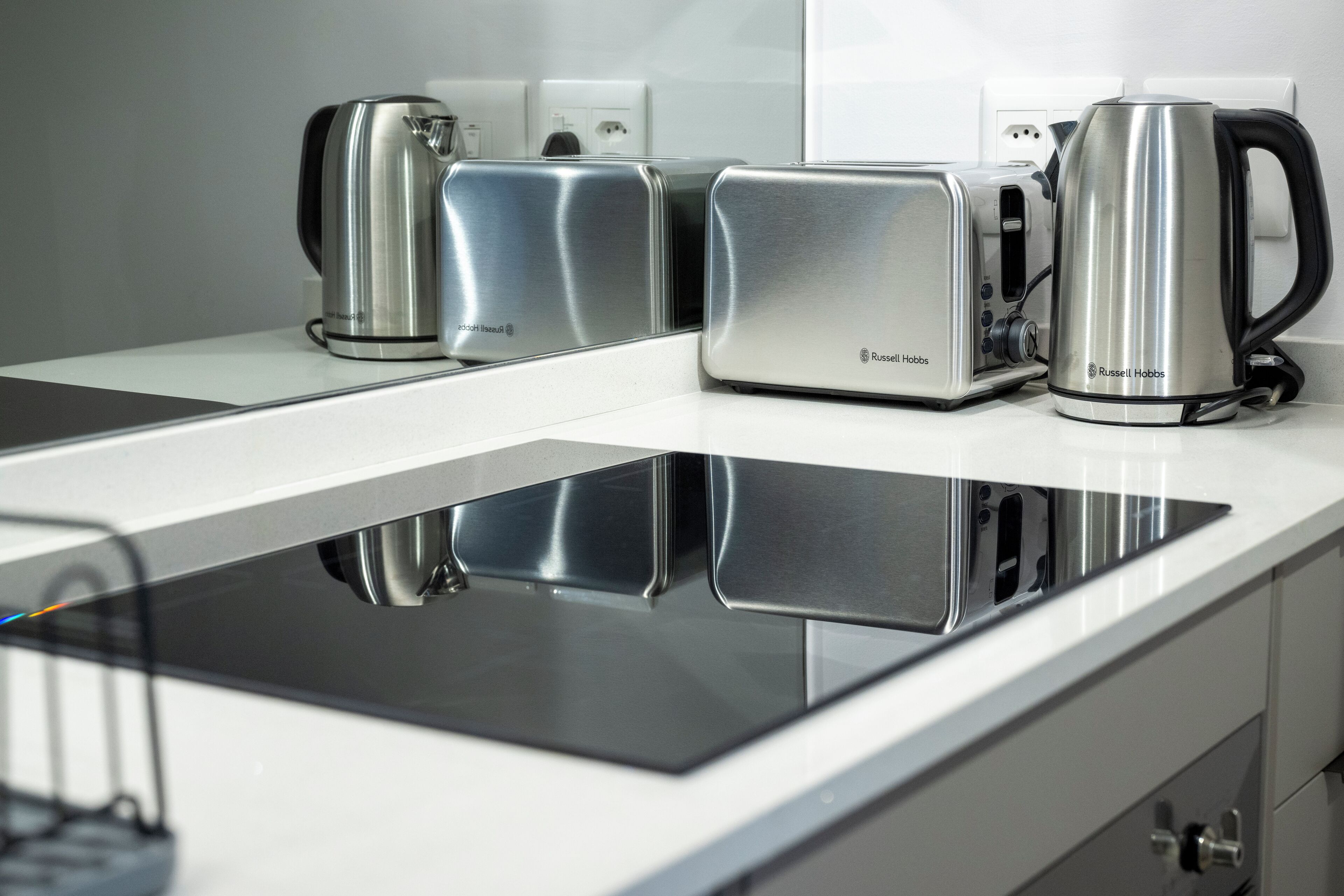 A modern kitchen with a built-in induction cooktop, a toaster, and a kettle.