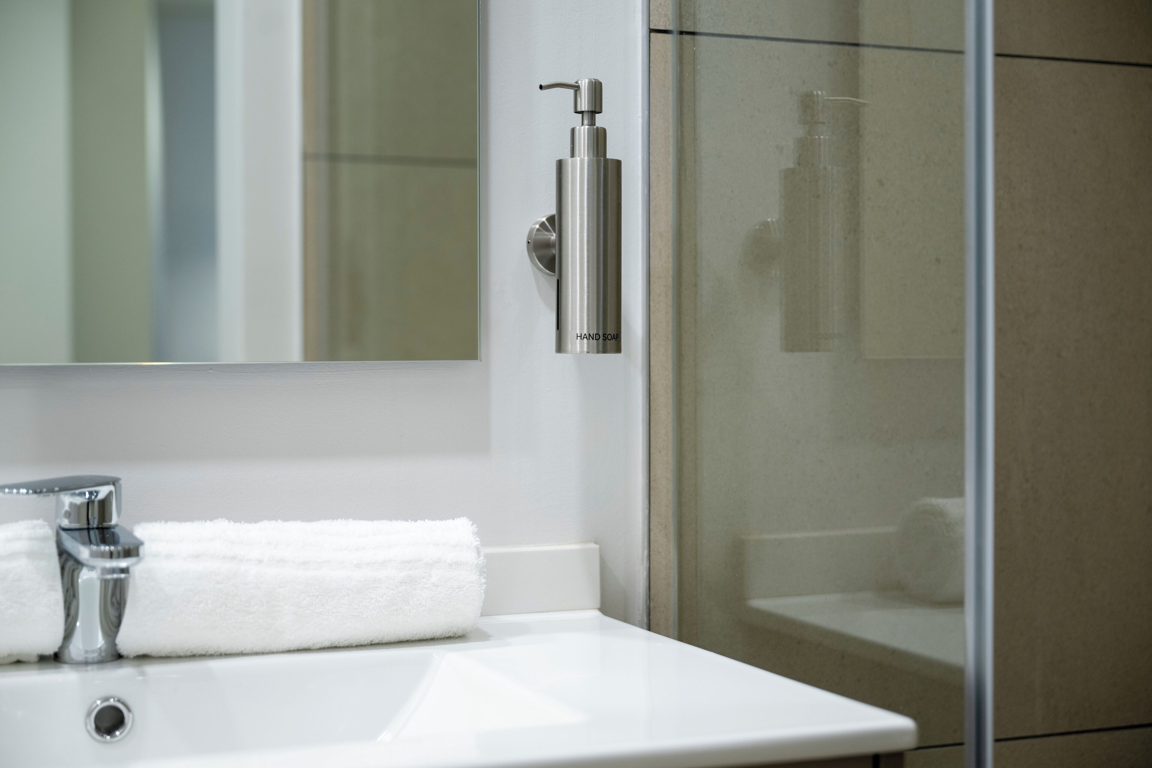 A bathroom with a white sink, a mirror, and a glass shower enclosure.