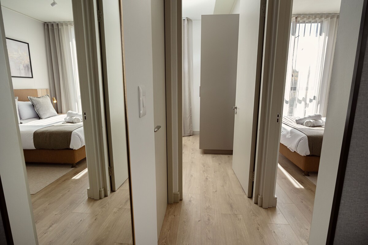 A hotel room with a bed, a wardrobe, and a bathroom visible through an open door.