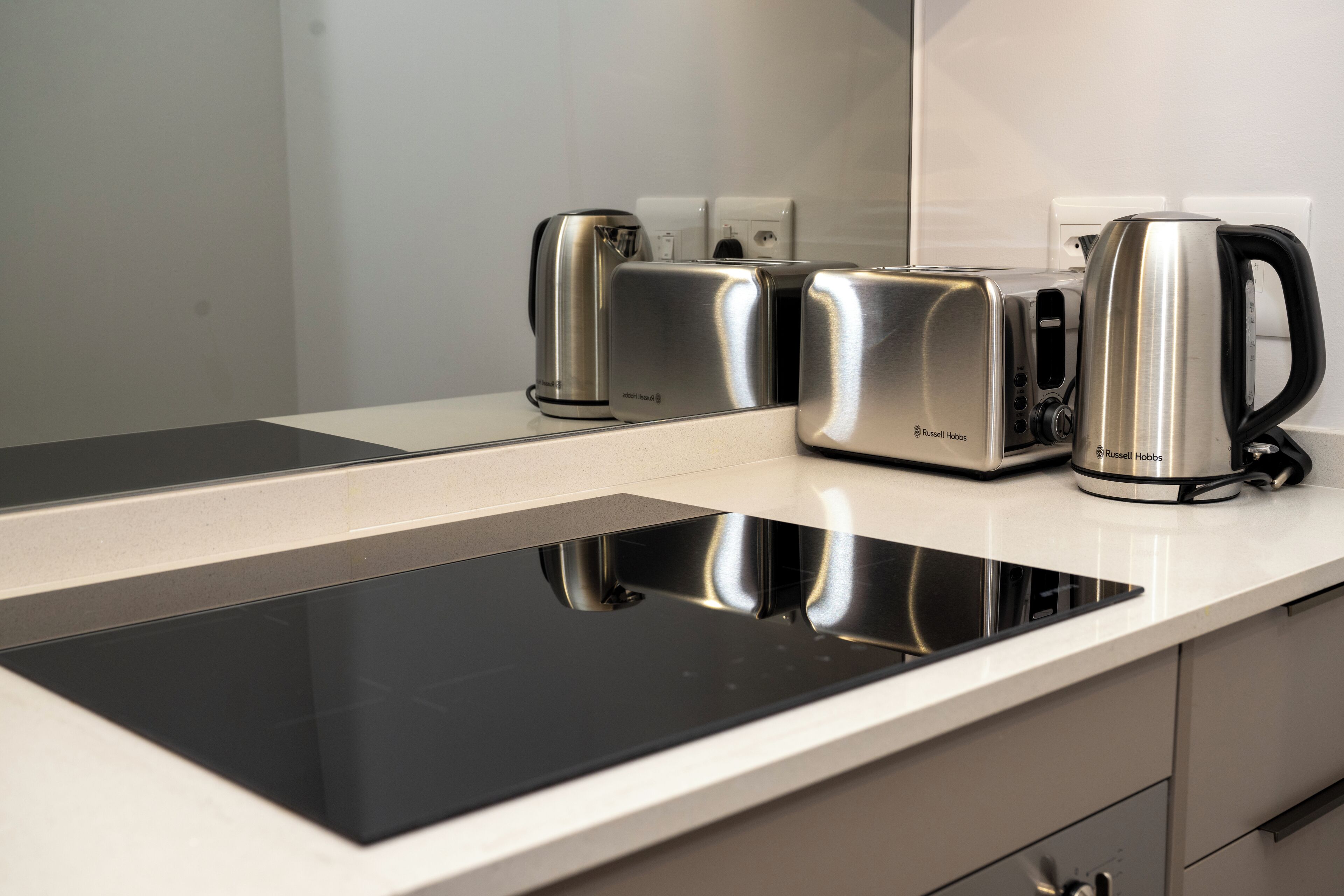 A modern kitchen with a built-in induction cooktop, a kettle, and a toaster.