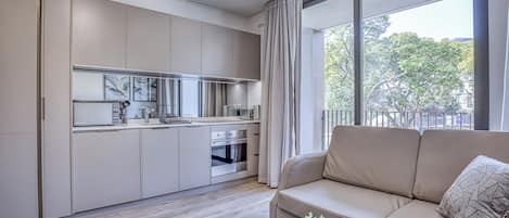 Un apartamento moderno con cocina, sofá y un amplio ventanal.
