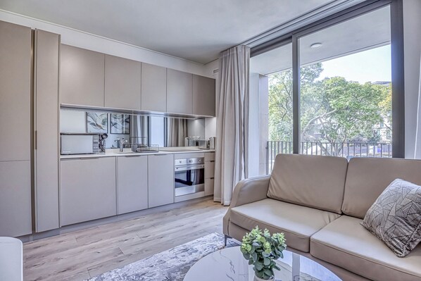 A modern apartment with a kitchen, a sofa, and a large window.