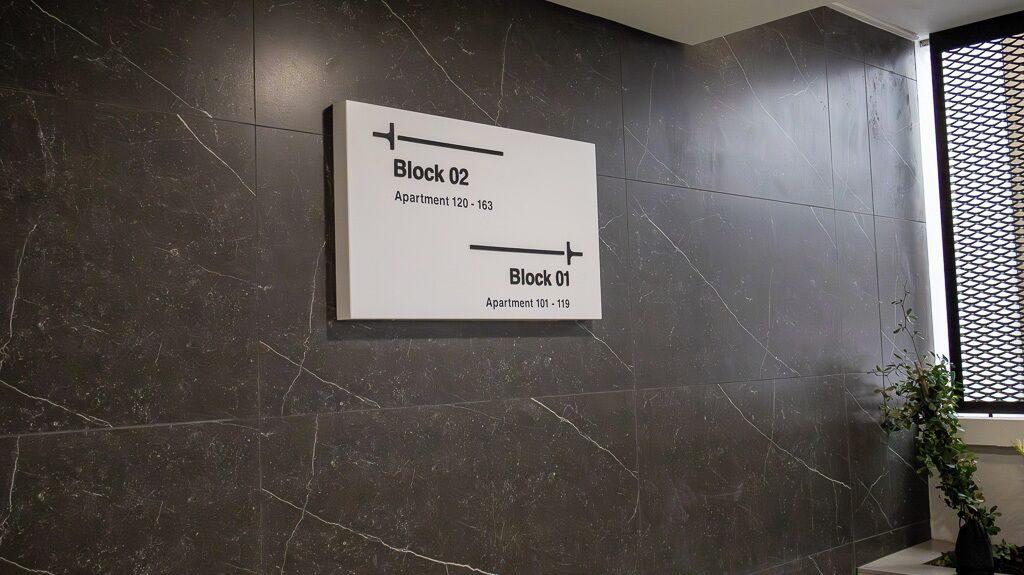A wall-mounted sign indicating Block 02 and Block 01 with apartment numbers.