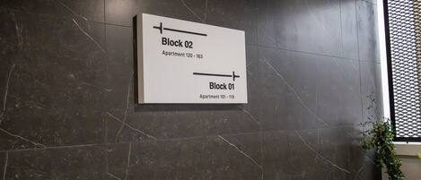 A wall-mounted sign indicating Block 02 and Block 01 with apartment numbers.