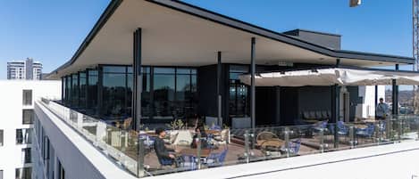 A modern outdoor seating area with glass railings and a covered section.