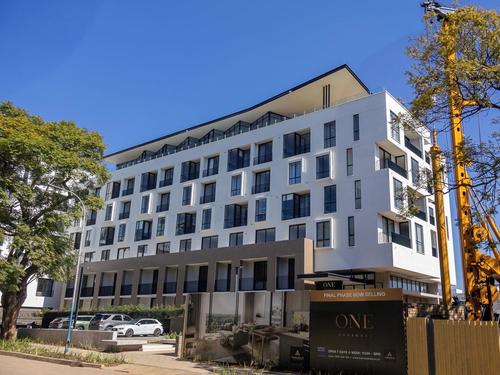 Un hotel de varios pisos con un diseño moderno, que presenta una entrada destacada con un letrero que indica la fase final de construcción.