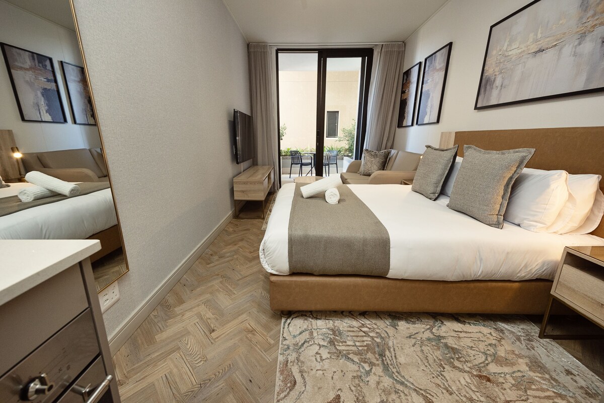A hotel room with a large bed, a desk, a chair, and a TV.