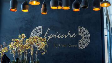 A wall with the text "Epicure by Chef Coco" and hanging pendant lights.