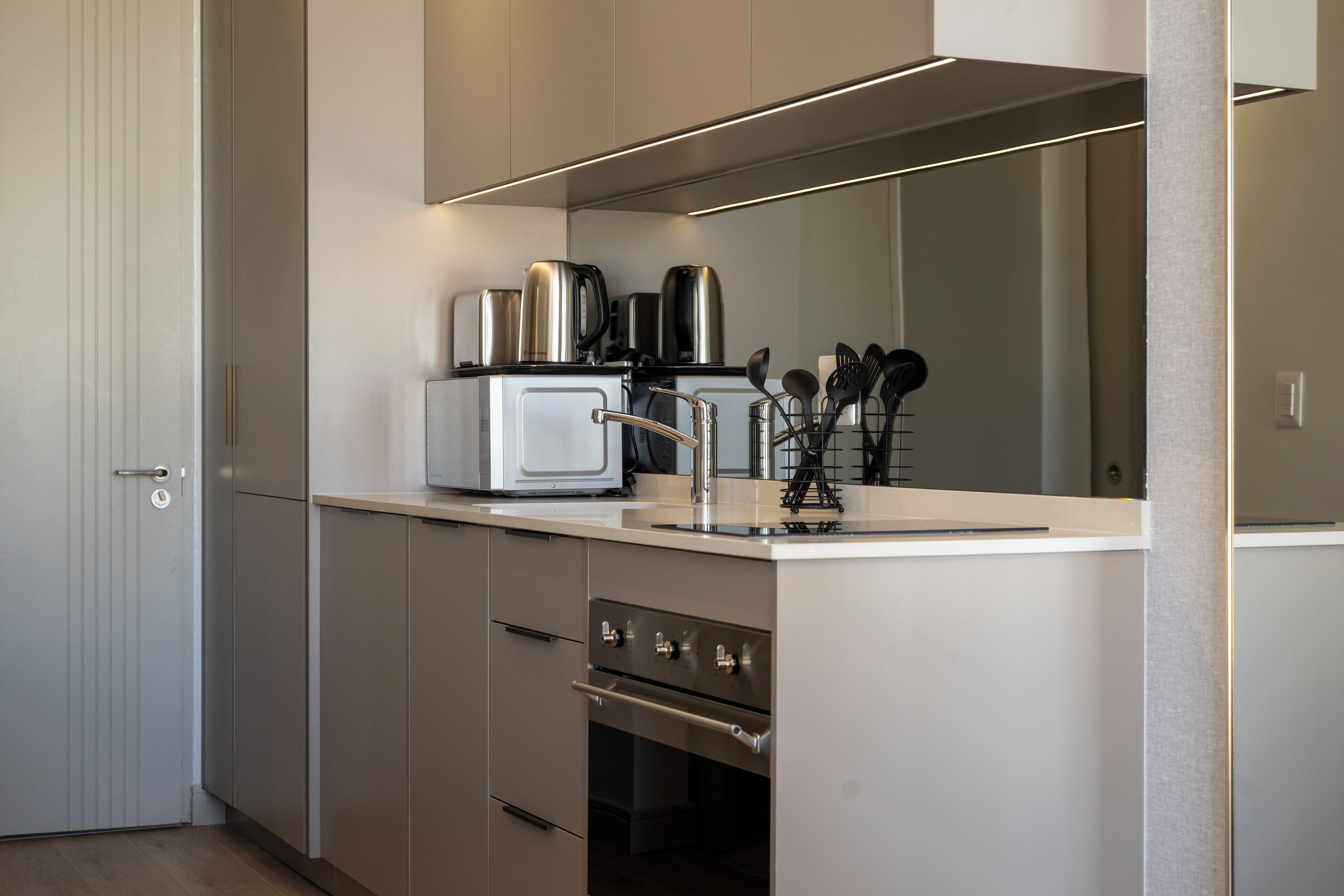 A modern kitchen with stainless steel appliances, a built-in oven, and a countertop with a coffee maker and utensils.