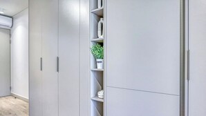 A modern, minimalist closet with built-in shelves and a potted plant. - One Rosebank Executive Apartment Hotel (Johannesburg)