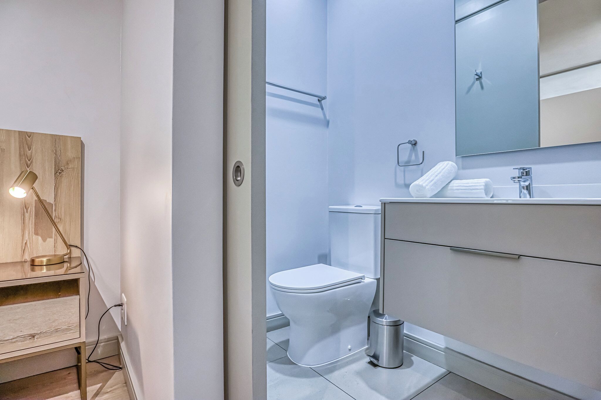 A modern bathroom with a toilet, sink, and mirror.