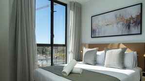 A hotel room with a large bed, a view of a construction site, and a painting on the wall. - One Rosebank Executive Apartment Hotel (Johannesburg)