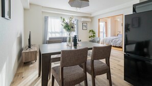 A modern living room with a dining area, a black refrigerator, and a large window with curtains. - E-US NAEBO1002 (Sapporo)