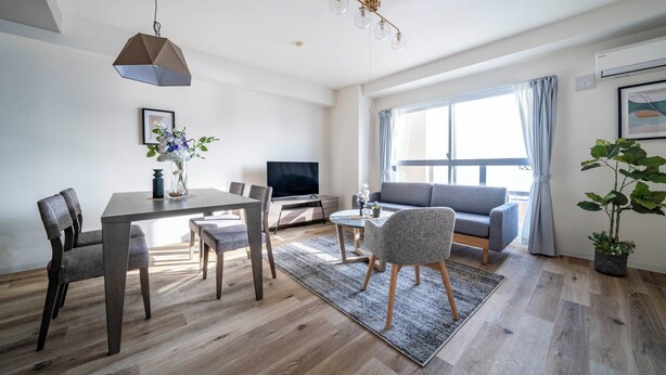 A modern living room with a dining area, a sofa, a TV, and a large window with curtains. - E-US NAEBO1002 (Sapporo)