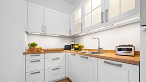 A modern kitchen with white cabinets, a wooden countertop, a sink, and a built-in radio. - Premium vacation apartment in the heart of Westerland on Sylt (Sylt)