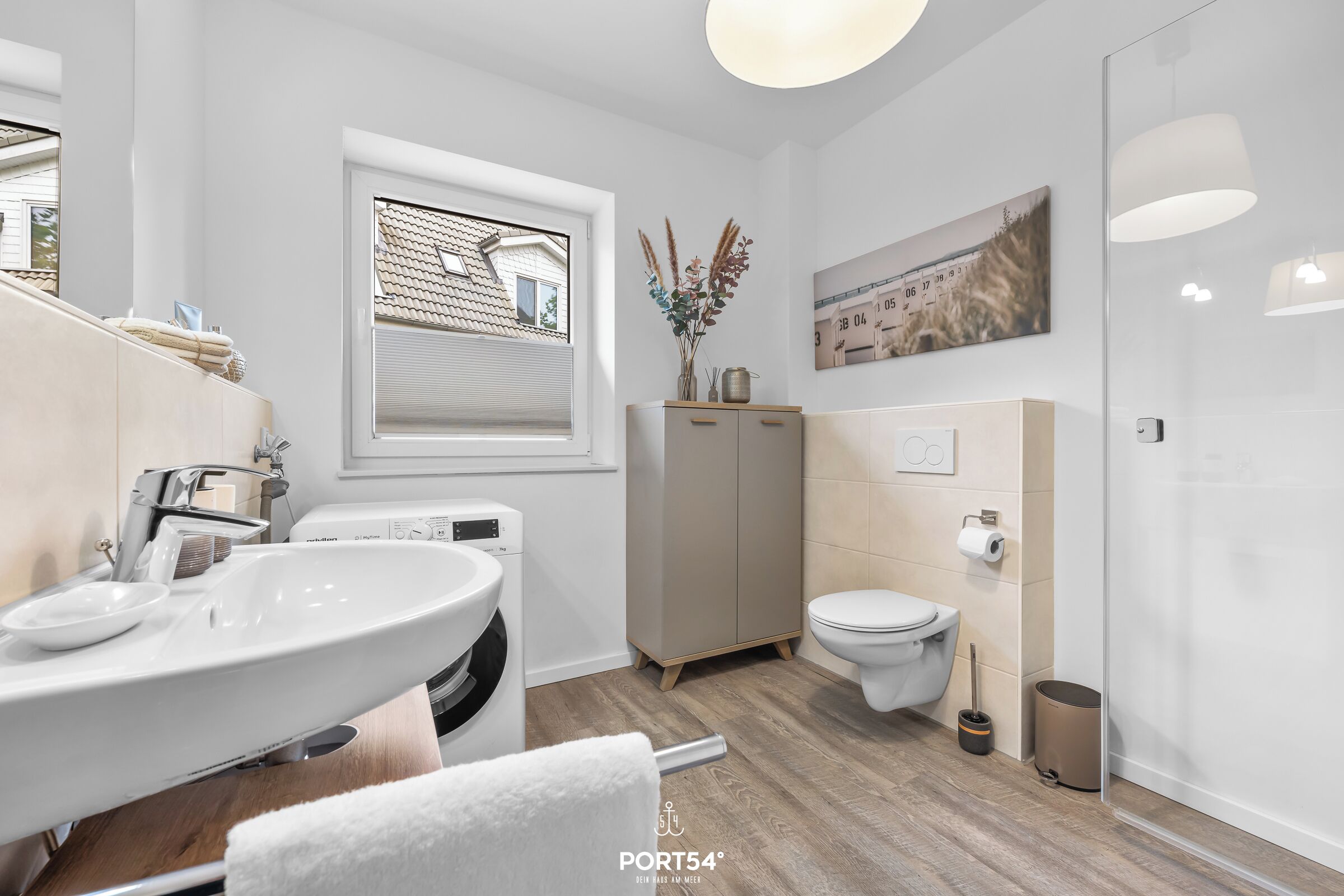 Ein modernes Badezimmer mit Waschbecken, Toilette und Fenster.