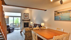 A cozy living room with a fireplace, a dining table, and a sofa.