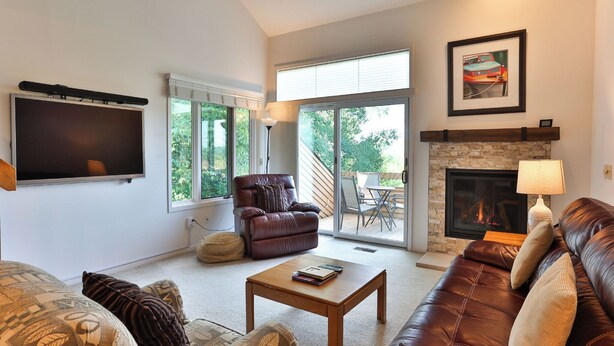 A living room with a leather sofa, a wooden coffee table, a fireplace, and a TV mounted on the wall.
