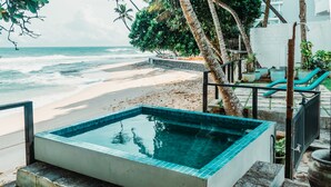 A rectangular pool with a tiled edge, surrounded by a stone deck and a railing. - Marleys Beach House (Talpe)