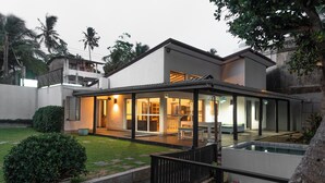 A modern house with a covered patio, a swimming pool, and a well-maintained garden. - Marleys Beach House (Talpe)